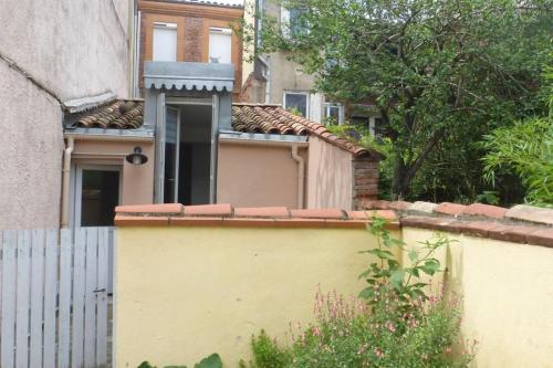 une maison jaune avec une clôture devant elle dans l'établissement Apartement au calme, cour, près du métro, centre, à Toulouse