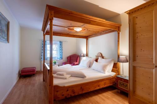 una camera da letto con letto a baldacchino in legno e cuscini bianchi di Familienfreundliche Ferienwohnung mit eigener Terrasse, FeWo 8 a Thiersee