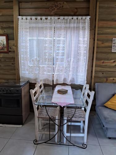 a table and chairs in a room with a window at Chalés Lar Doce Mar Camacho SC in Jaguaruna