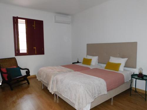 a bedroom with a large bed and a chair at Casa dos Primos in Muxagata