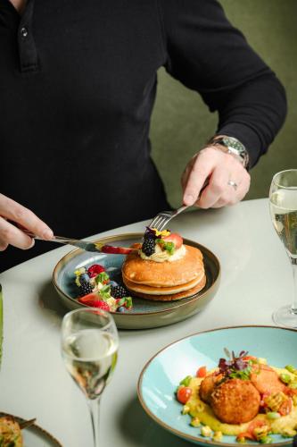 a person cutting a plate of pancakes with a fork and knife at St. James' Court, A Taj Hotel, London in London