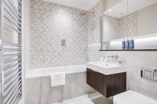 a bathroom with a sink and a tub and a toilet at Luxury Apartments near Canary Wharf in London