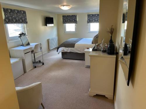 a bedroom with a bed and a desk and a sink at Oronsay Guest House in Alnwick
