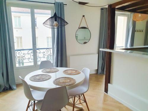 une salle à manger avec une table et des chaises blanches dans l'établissement EXIGEHOME - Beau duplex-15 min Paris/La Défense/Champs Elysées, à Suresnes