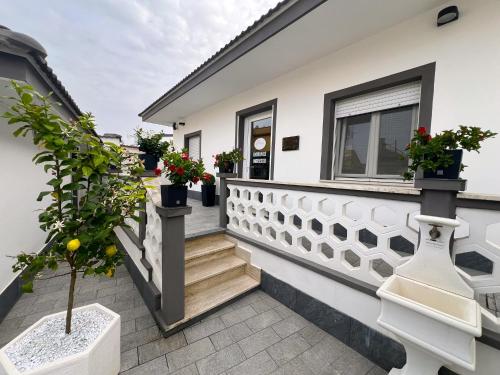 a white house with potted plants on the balcony at Kalasó Design Guest House in Fiumicino