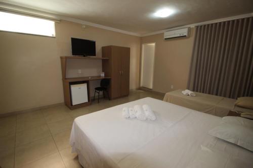 a hotel room with two beds and a television at Hotel Regina Muriaé in Muriaé