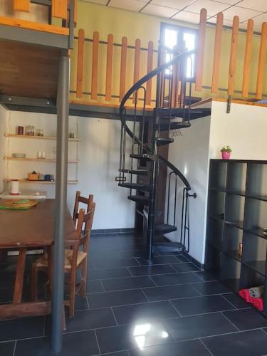 a room with a table and a spiral staircase at Loft immerso nel bosco in Rivola