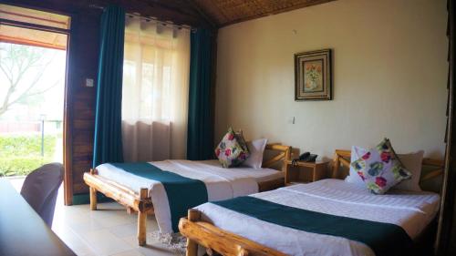 two beds in a room with a window at ATACO COUNTRY RESORT in Fort Portal