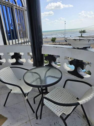 un tavolo in vetro e sedie su un balcone con vista sulla spiaggia di Brise de mer L'écume a La Plaine