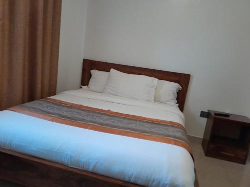 a bed with a wooden headboard in a room at Infinity Hotel Kampala in Kampala