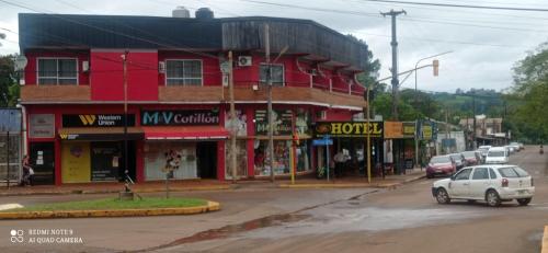 un bâtiment rouge au coin d'une rue avec des voitures dans l'établissement Hotel Don Enrique, à El Soberbio