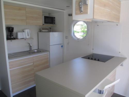 une cuisine blanche avec un évier et un plan de travail dans l'établissement mobil home o'hara, à Poilly-lez-Gien