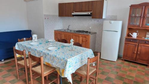 uma cozinha com uma mesa com cadeiras e um frigorífico em Appartamento 'il cortiletto' em Porto Ottiolu