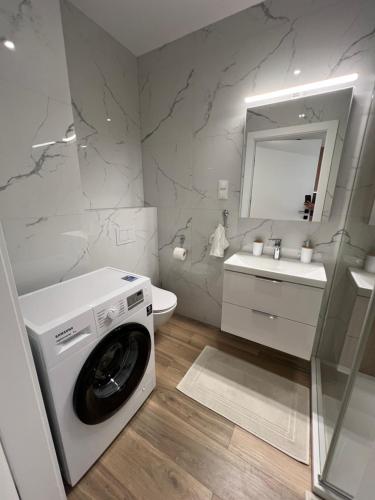 a white bathroom with a washing machine and a sink at Apartament Broniewskiego in Busko-Zdrój