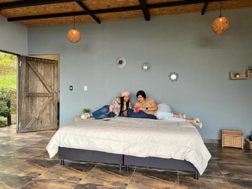 Due donne sedute su un letto in una camera da letto di Ecovillage glamping Idilio a Llanitos