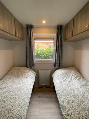 two beds in a small room with a window at Chalet vakantiepark Beekbergen in Beekbergen