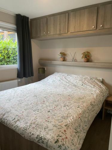 a bedroom with a bed with a floral bedspread at Chalet vakantiepark Beekbergen in Beekbergen