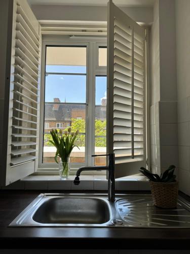 a kitchen sink in front of a window with shutters at Modern Flat in Maida Vale in London