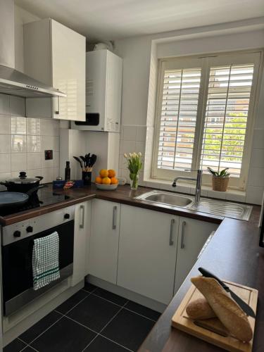 a kitchen with white cabinets and a sink at Modern Flat in Maida Vale in London