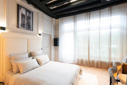 a bedroom with a white bed and a window at SAINT-LOUIS APARTMENT - LUXURY HIGH END RENOVATED Apartment - HEART OF LE MARAIS - HOTEL DE VILLE in Paris
