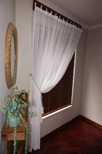 a window with a white curtain in a room at The Leopard Tree in Polokwane