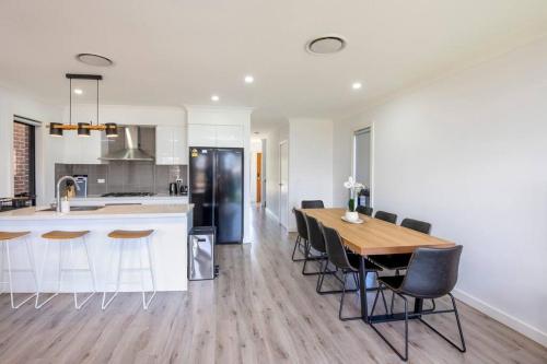 a kitchen and dining room with a wooden table and chairs at Lovely 4 bedrooms house to Ed station in Ingleburn