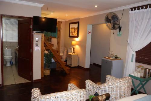 a living room with a couch and a staircase at The Leopard Tree in Polokwane