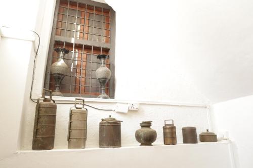 een plank met potten en vazen aan de muur bij Prag View Heritage Homestay in Bhuj