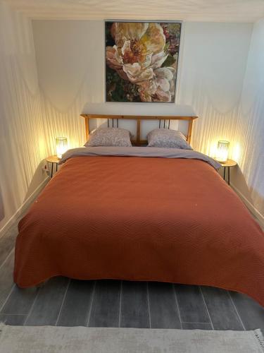 - une chambre avec un grand lit orange et deux lampes dans l'établissement Les Mirabelles, à Ensisheim