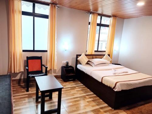 um quarto com uma cama e uma mesa e algumas janelas em Hotel Sonar Tori em Gangtok