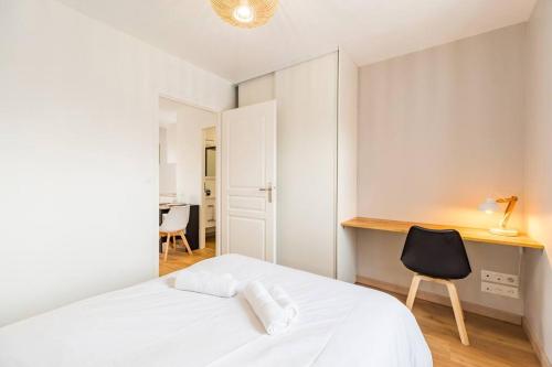 Schlafzimmer mit einem weißen Bett und einem Schreibtisch in der Unterkunft Escale paisible appartement proche Guingamp in Grâces