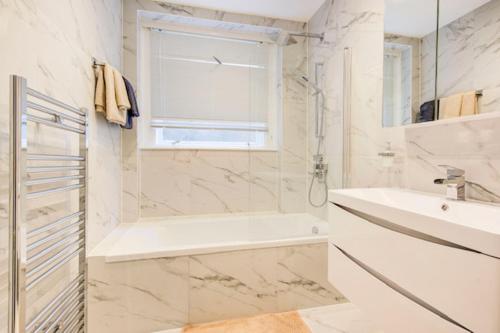 Baño blanco con bañera y lavamanos en Beautuful 2 bed apartment in central London, en Londres