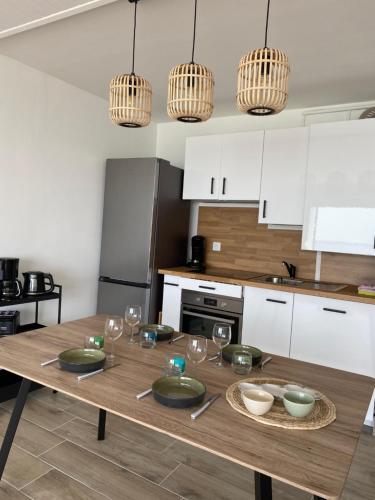 - une cuisine avec une table en bois et des verres dans l'établissement VUE BAIE La Sauvagine 1, au Crotoy