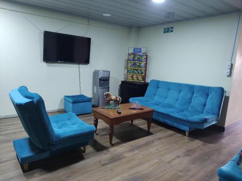a living room with blue couches and a table and a tv at Hostal Carvajal in Bogotá