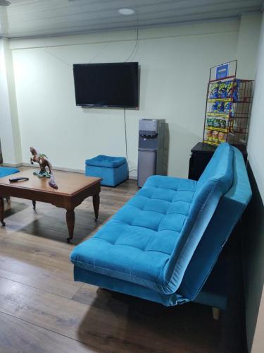 a living room with a blue couch and a table at Hostal Carvajal in Bogotá