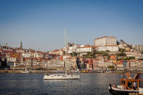a white sailboat in the water in front of a city at 480 Liberdade Apartamento in Labruge