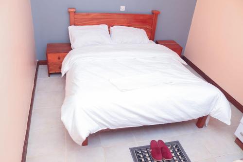 a bedroom with a bed with two red shoes on the floor at Tamwe ltd Airbnb &studios in Meru