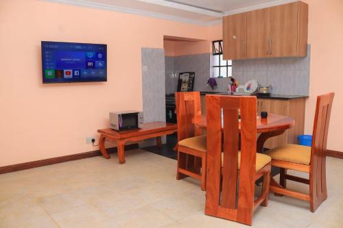 a kitchen with a table and a tv on the wall at Tamwe ltd Airbnb &studios in Meru