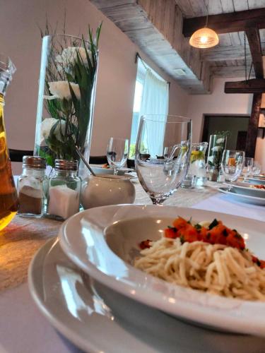 a plate of pasta on a table with wine glasses at KAMIENICA Pokoje & Restauracja in Opalenica
