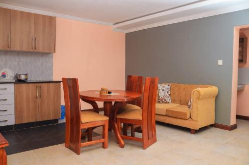 eine Küche mit einem Tisch, einem Stuhl und einem Sofa in der Unterkunft Tamwe ltd Airbnb &studios in Meru