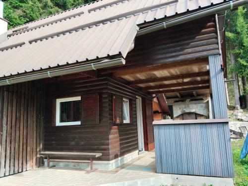 eine Holzhütte mit einer Bank unter einem Dach in der Unterkunft Wooden Treasure in Jesenice