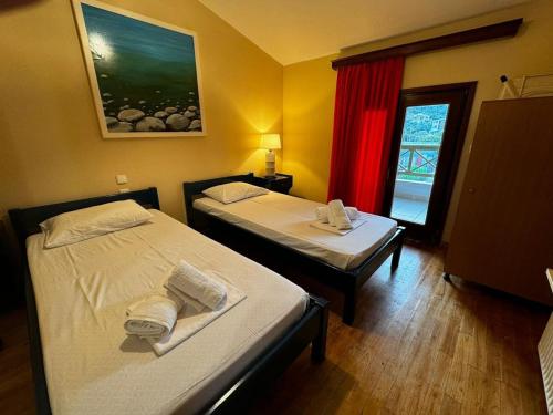 two beds in a small room with a window at Moonbeam Townhouse Skiathos in Skiathos
