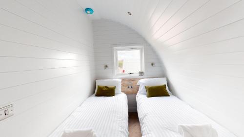 2 camas en una habitación pequeña con ventana en Byrnside Lodge, en Latheron