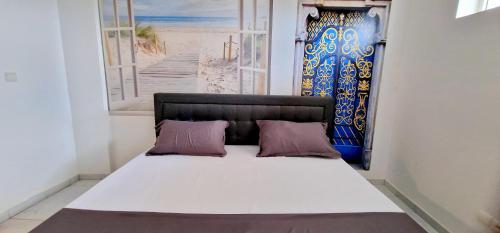 ein Bett mit zwei Kissen in einem Zimmer mit einem Fenster in der Unterkunft Évasion in Lomé