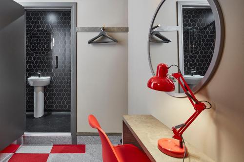 La salle de bains est pourvue d'une lampe rouge et d'un miroir. dans l'établissement The Pier Rooms, à Oban
