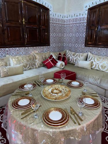 a living room with a table with plates and wine glasses at Riad malak in Marrakesh