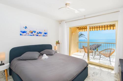 een slaapkamer met een bed en een balkon met uitzicht op de oceaan bij Roquebrune plage - Terrasse vue mer in Roquebrune-Cap-Martin