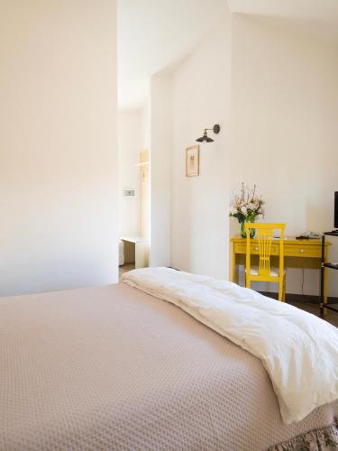 a white bedroom with a bed and a desk at Hotel Donatella in Posada