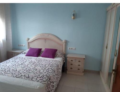 a bedroom with a bed with purple pillows and a night stand at Apartamento El Hammam in Empuriabrava