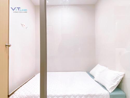 a small room with a bed with white sheets at The Sóng Hotel & Apartment Vũng Tàu in Vung Tau
